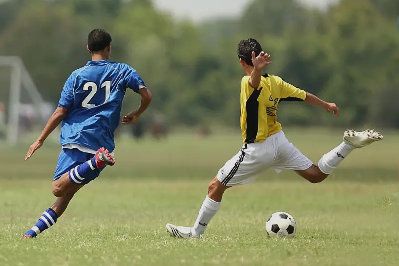 dois homens jogando futebol no campo