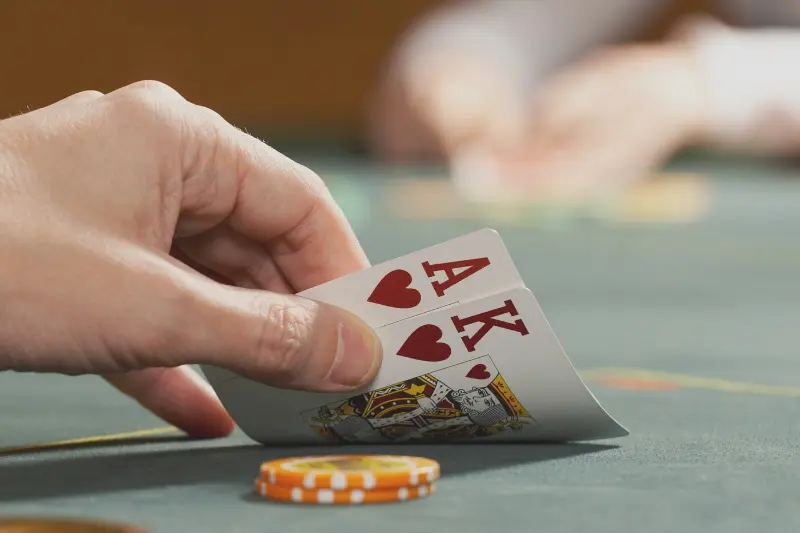 homem levantando cartas de pôquer com duas fichas